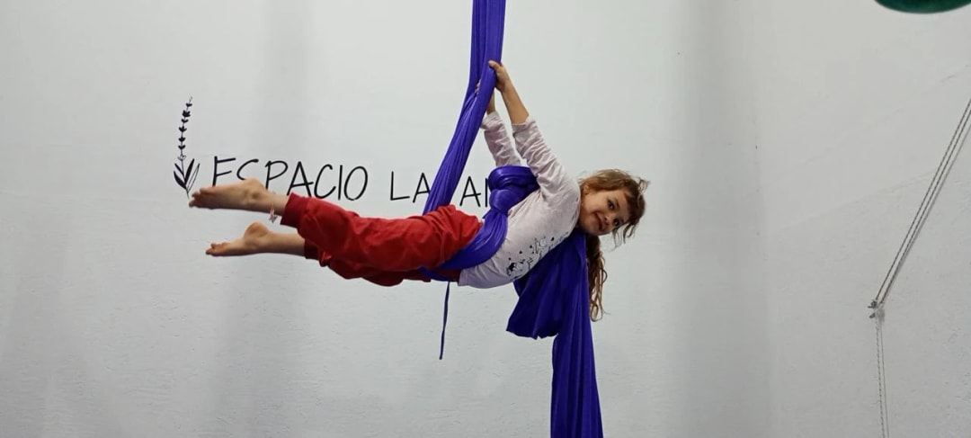 Nena recostada en las telas, sonriendo